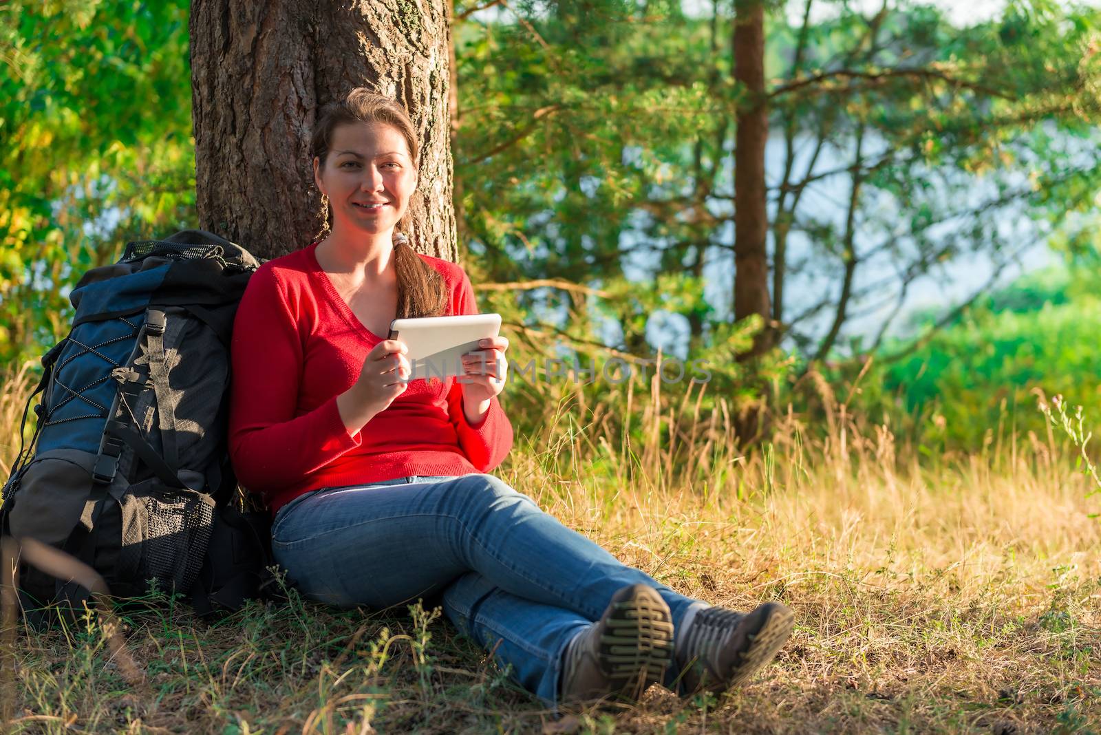 girl traveler resting in a tree with the tablet