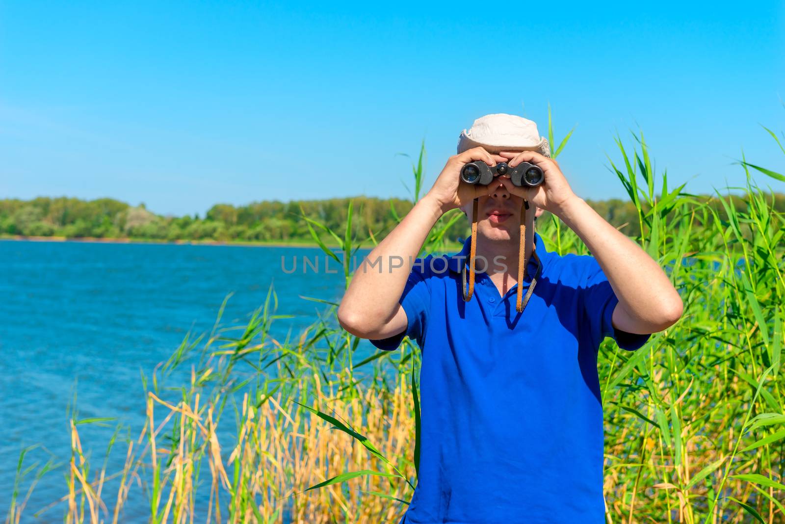 man in blue shirt is looking out for prey with binoculars