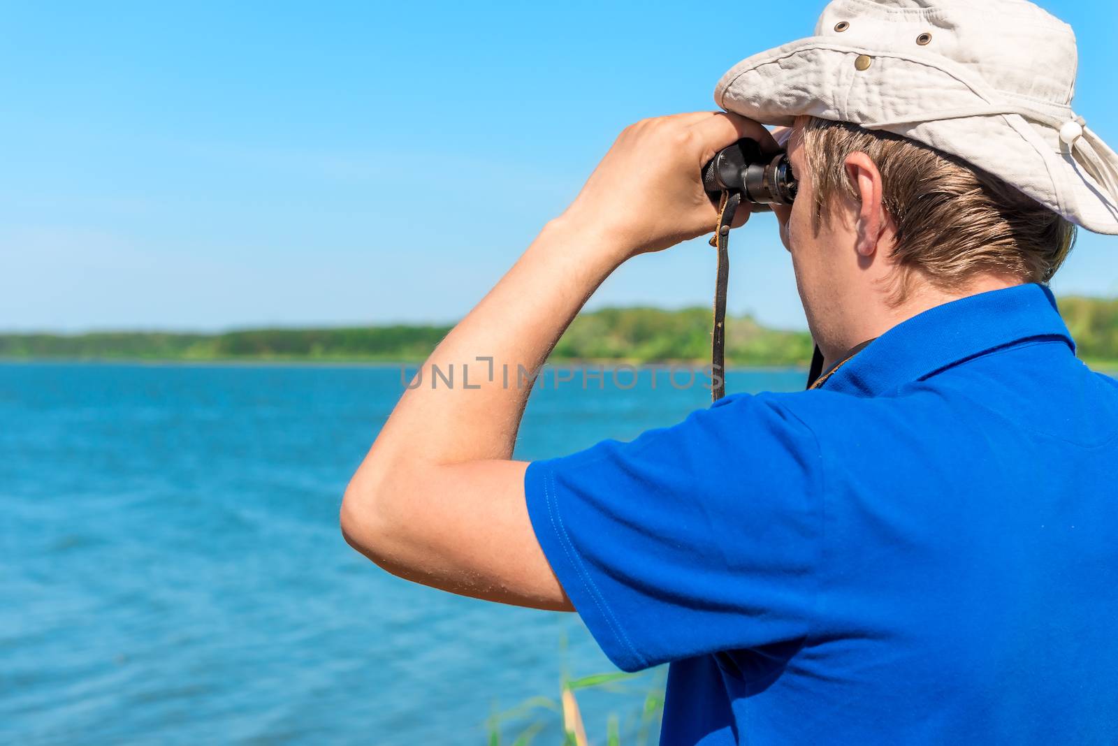 man with binoculars looks for something on the lake by kosmsos111