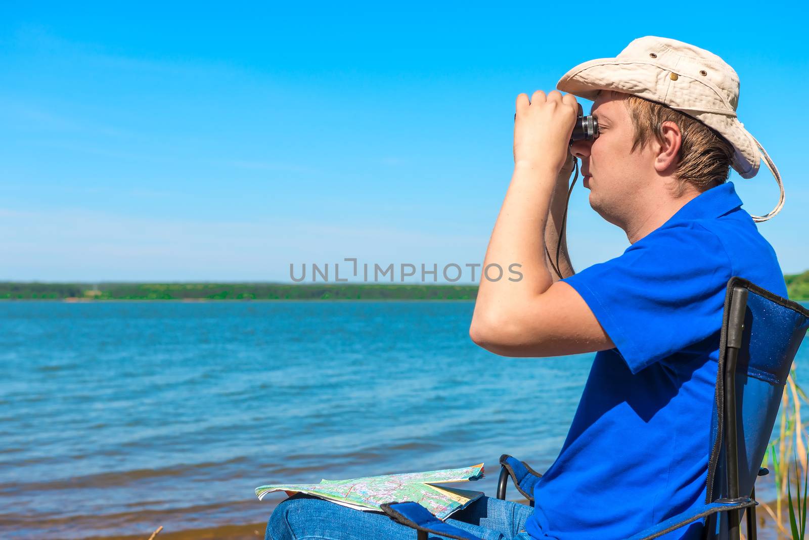 young man near the lake looking through binoculars