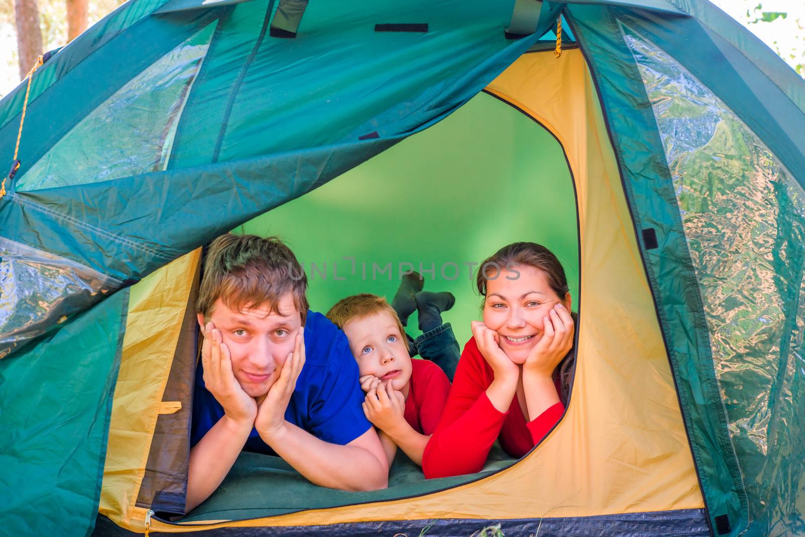 Family of three people resting in a tent
