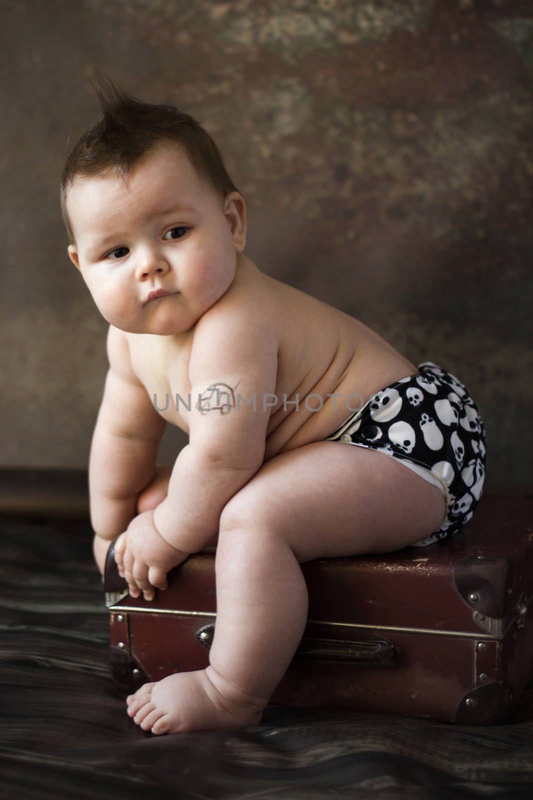 small boy sitting on suitcase