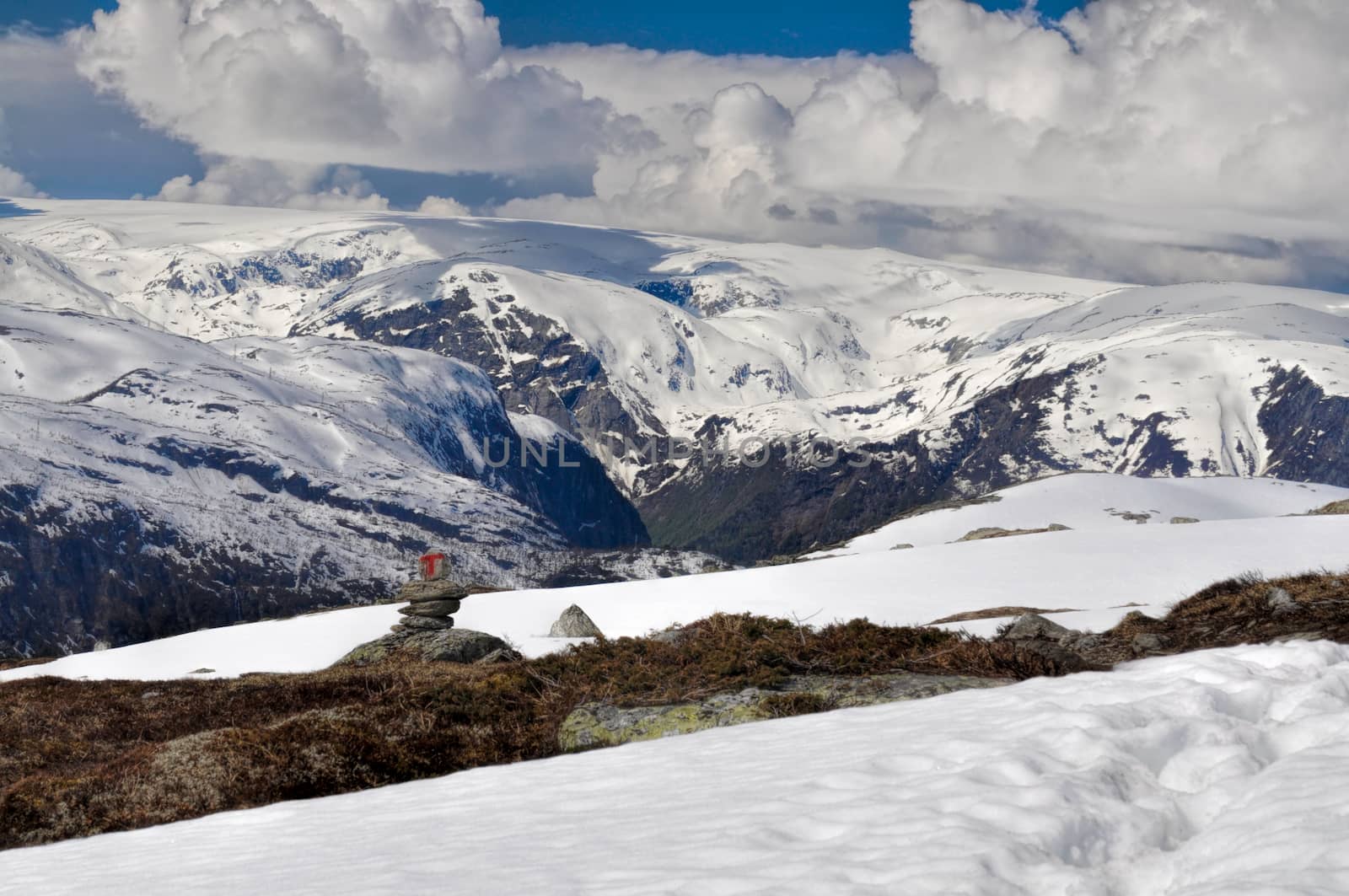 Clouds hanging low over the mossy mountain covered in snow near Trolltunga, Norway