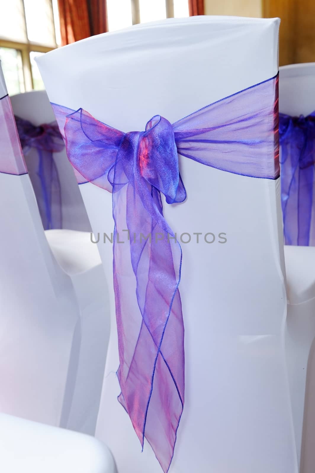 A chair covered with white and purple ribbon