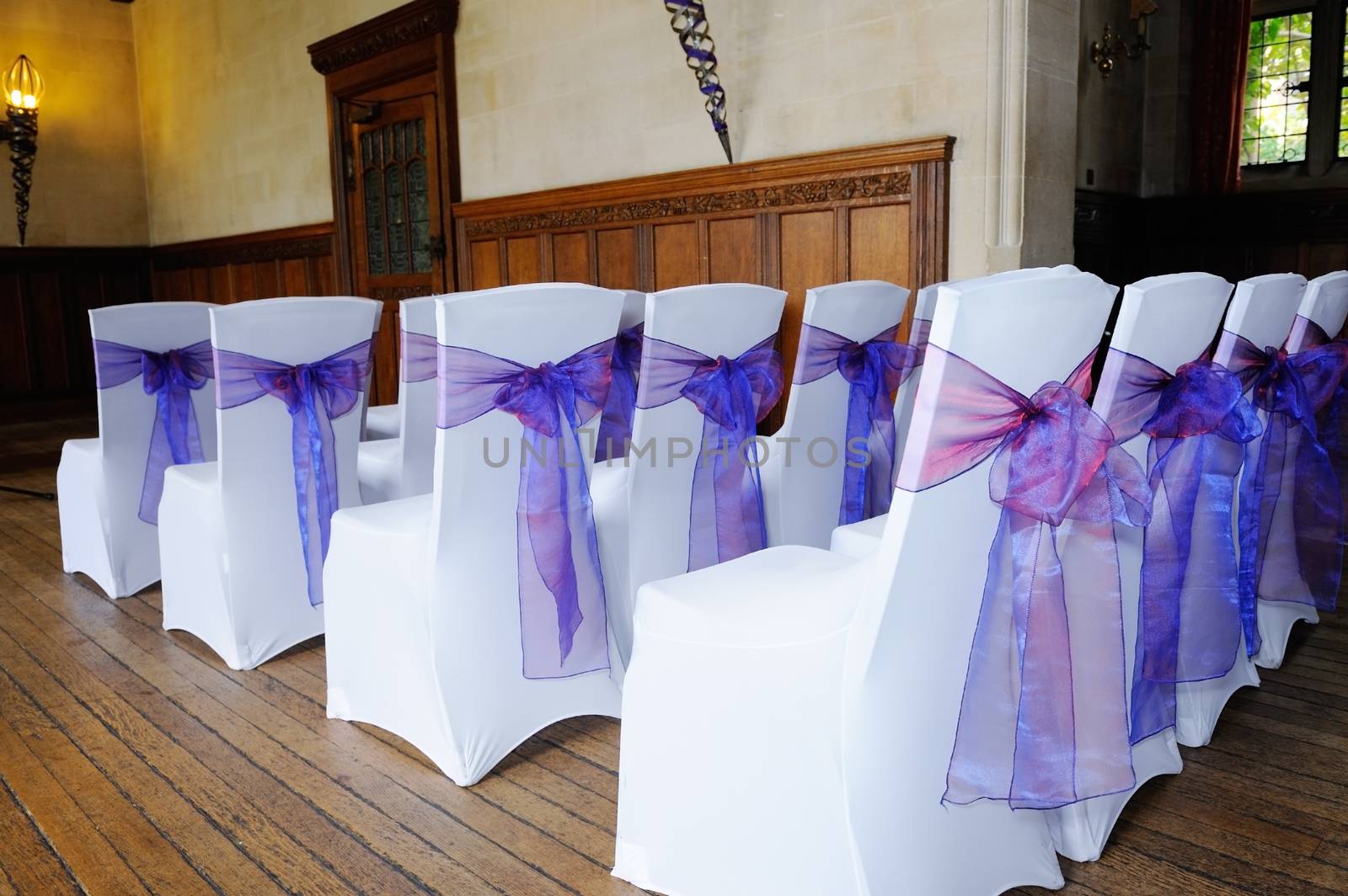 Chairs at wedding ceremony covered in white and purple