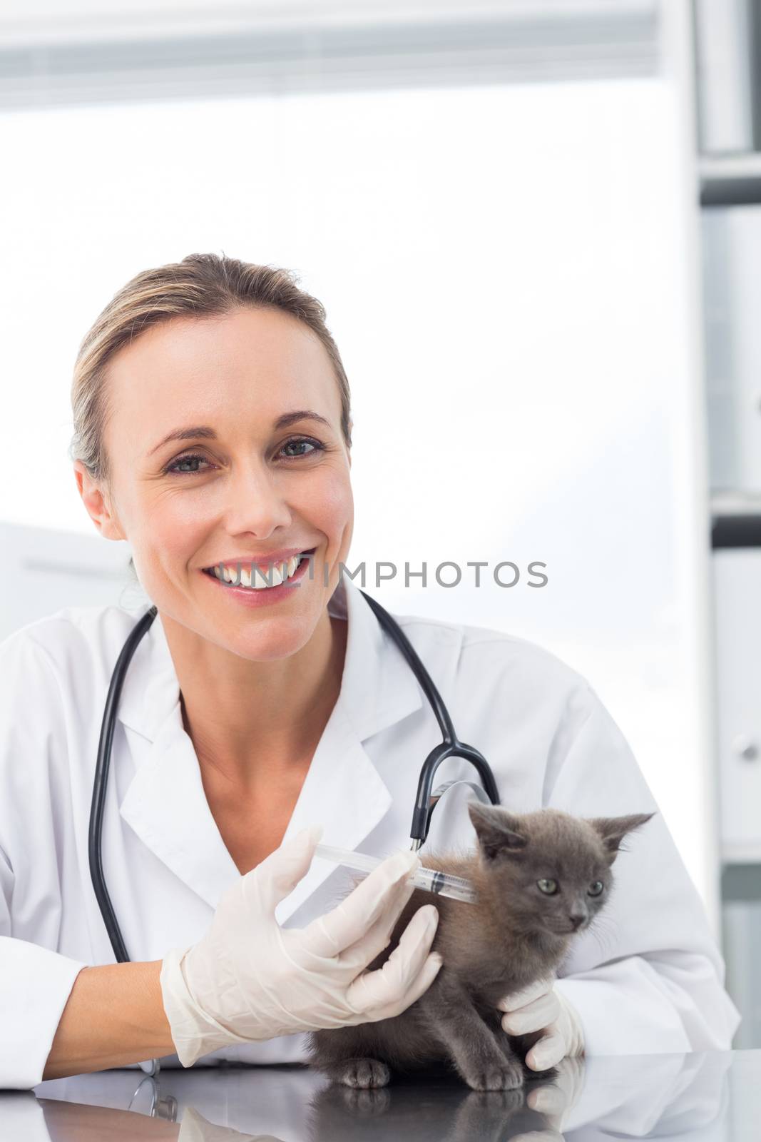 Portrait of smiling female vet injecting a kitten in clinic