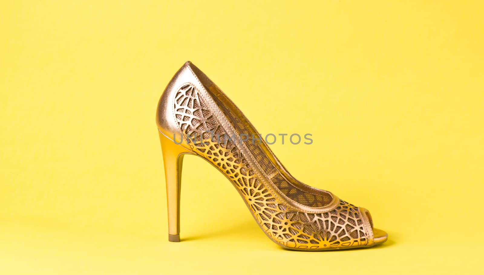 Woman gold shoes on yellow background