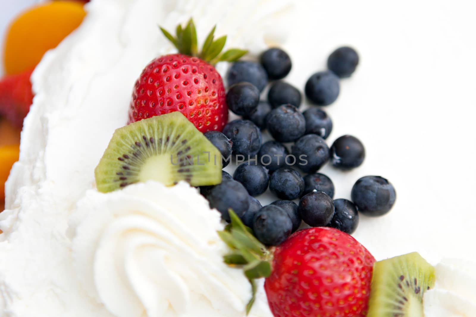 White frosted cake covered with fresh fruit toppings. Shallow depth of field.