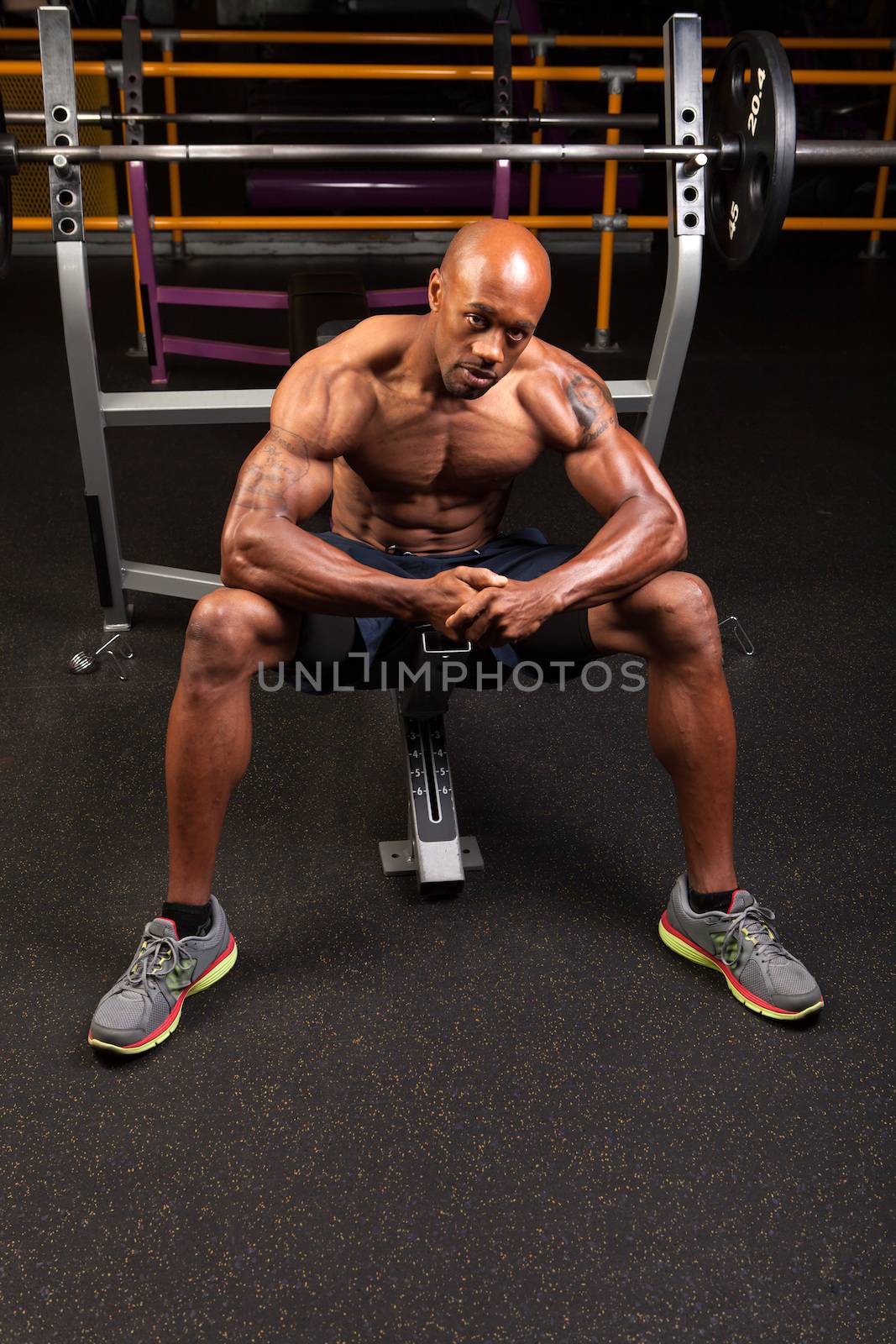 Weight lifter sitting at the bench press about to lift a barbell.