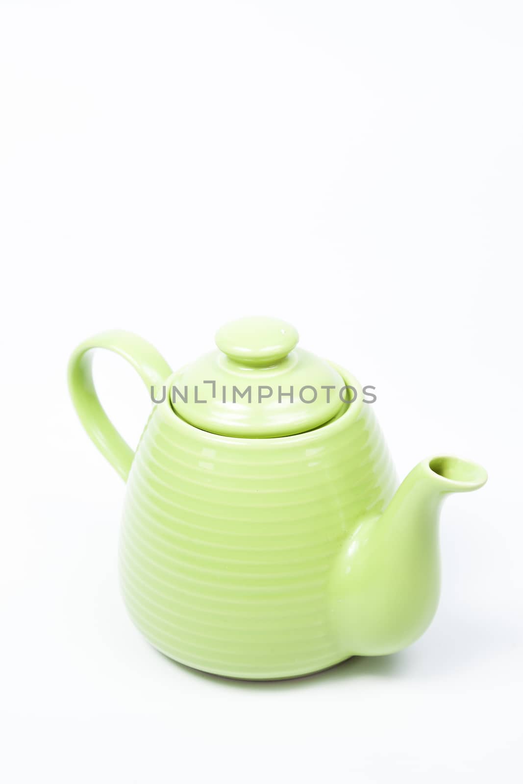Green teapot on a white background with a single in the studio.
