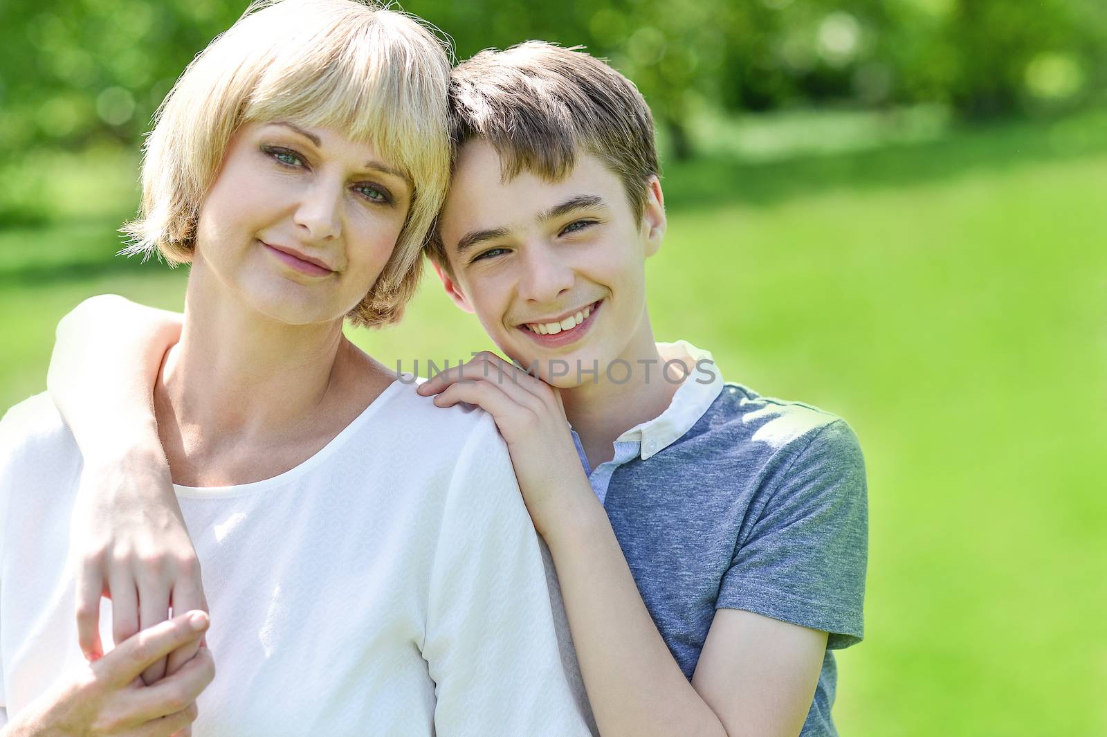 Smiling mother posing with her son, outdoors.