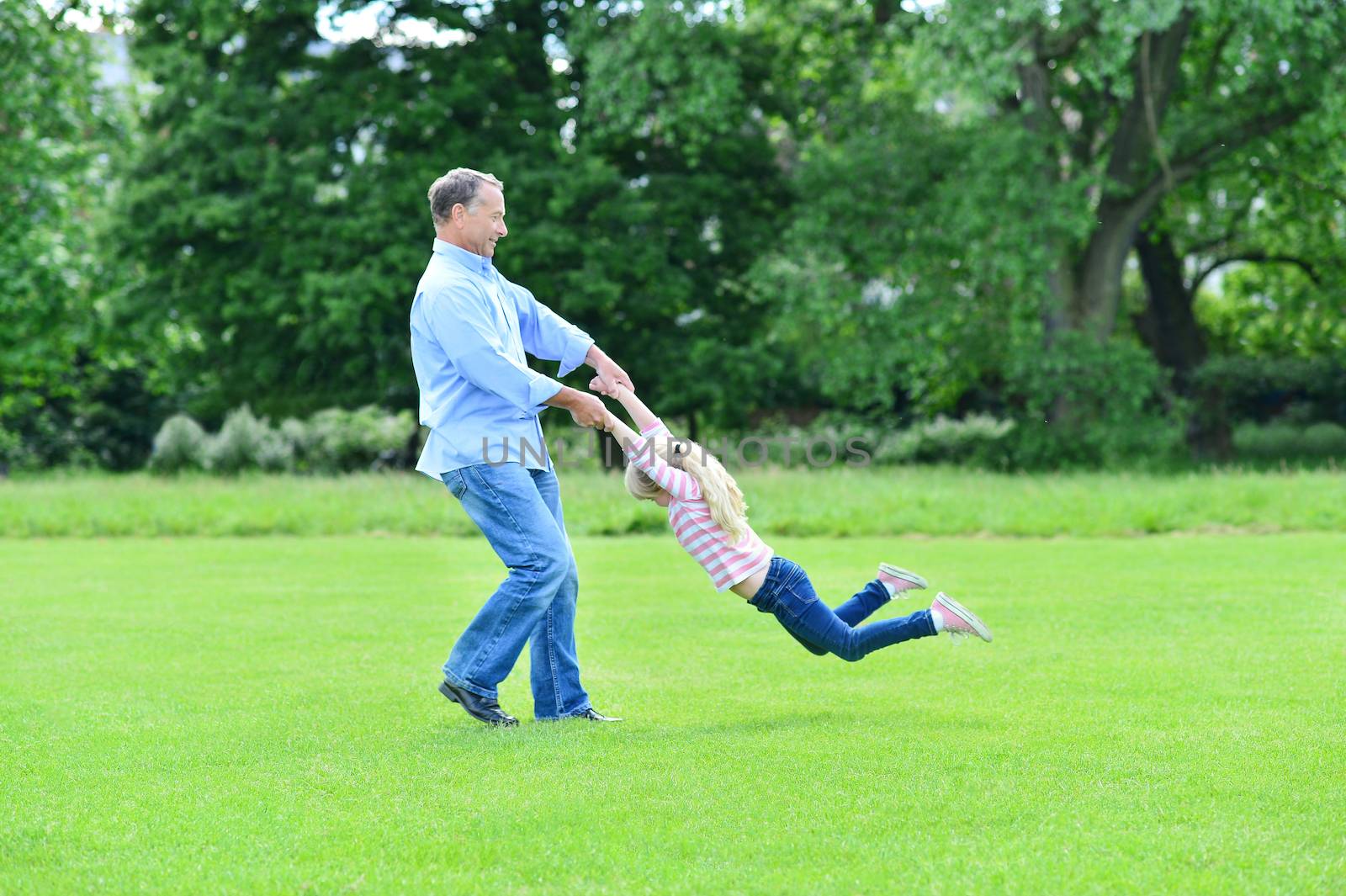 Playful father and daughter having fun in garden by stockyimages