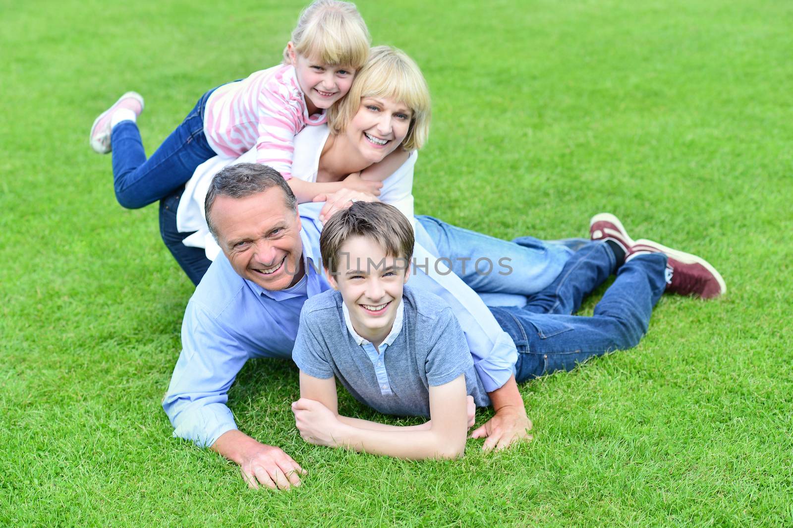 Family of four having fun outdoors by stockyimages