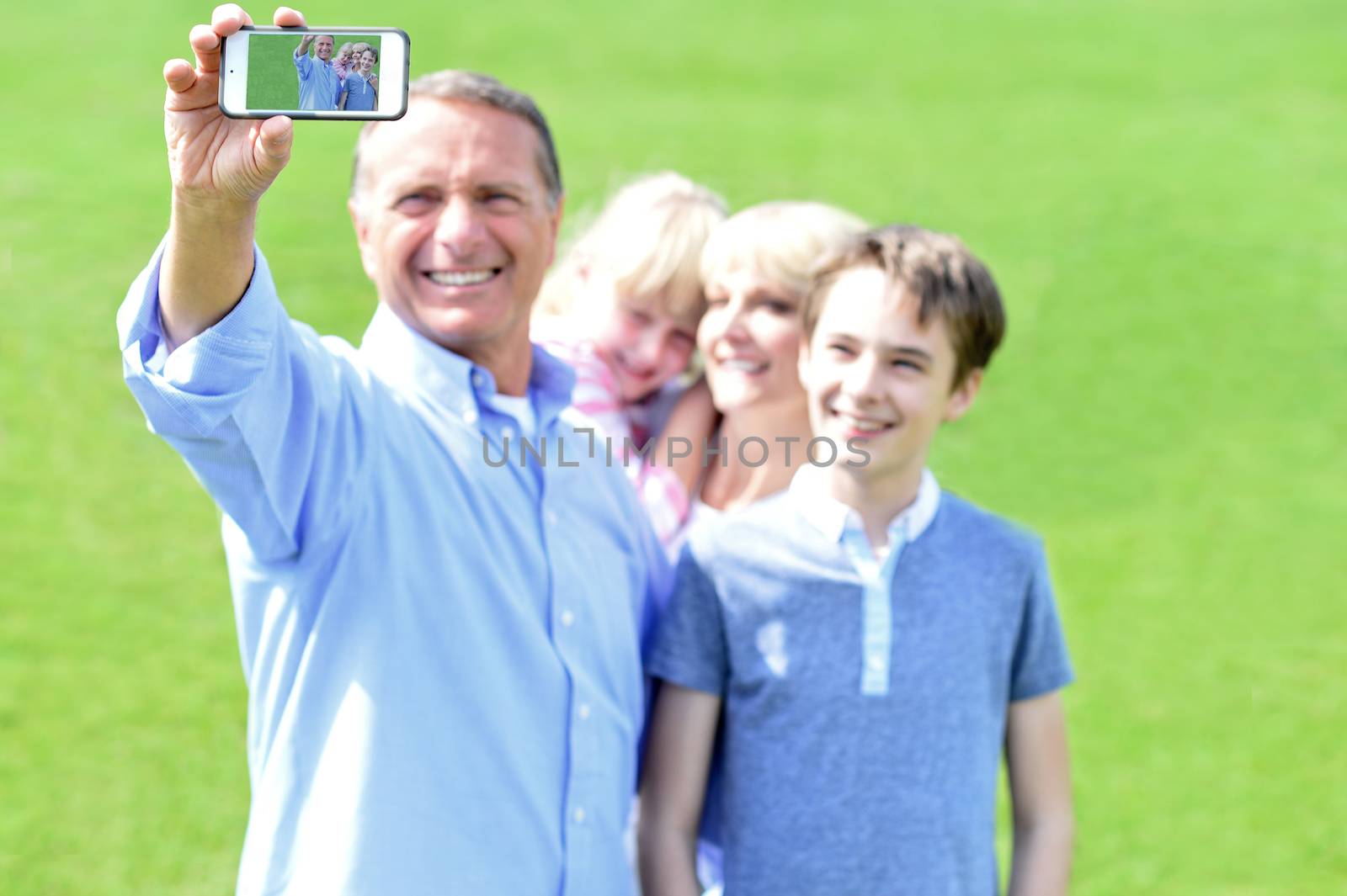 Father clicking family selfie, outdoors. by stockyimages