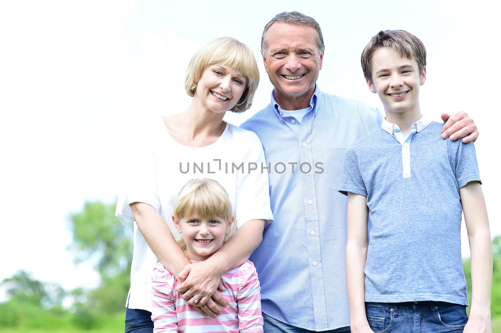 Happy family of four posing together in park