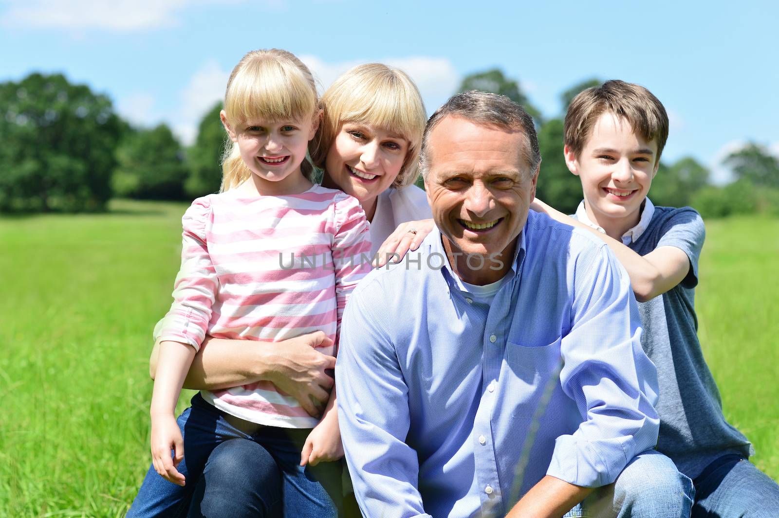 Joyful family of four on a bright sunny day by stockyimages