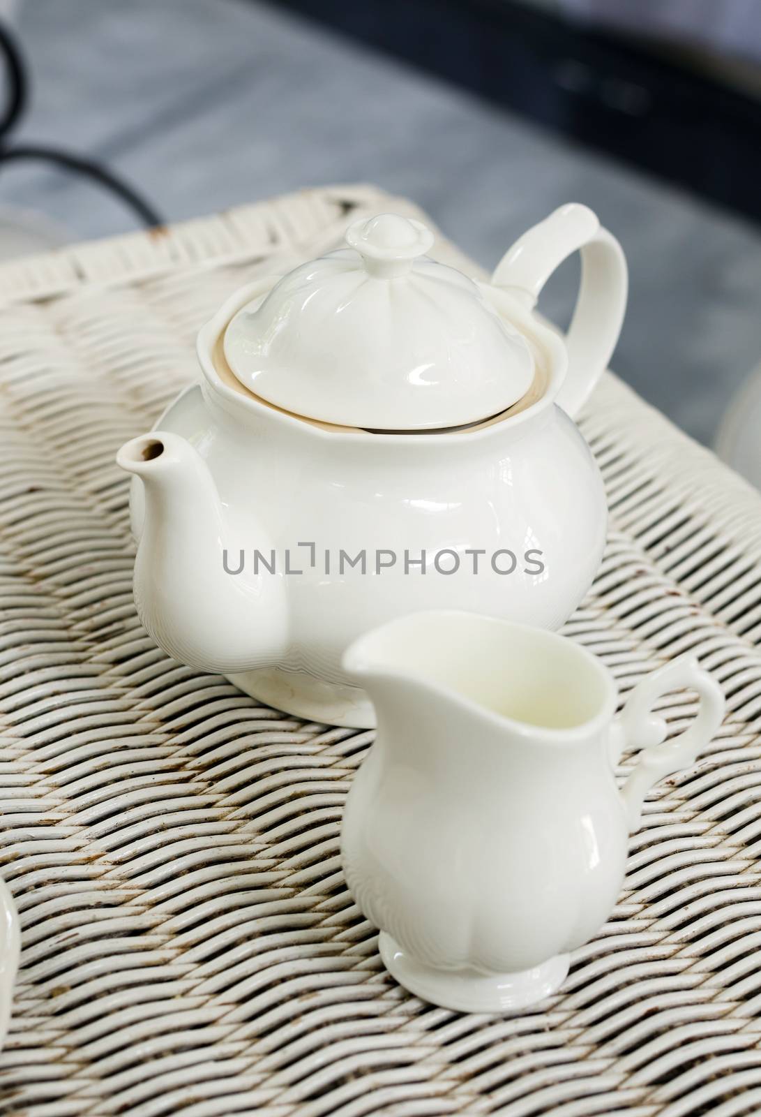 Teapot with little milk jar on weave texture background