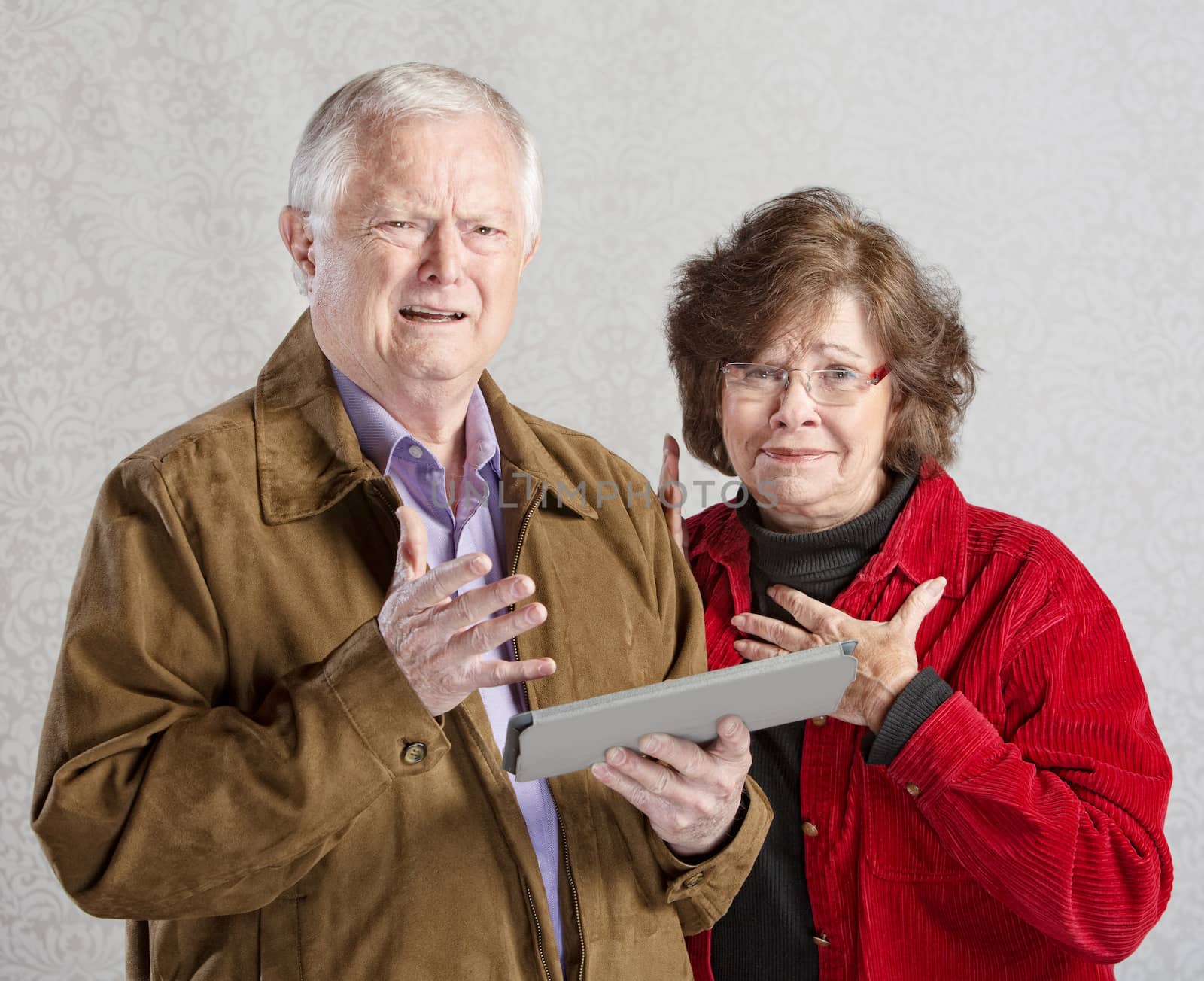 Perplexed man and woman holding computer tablet