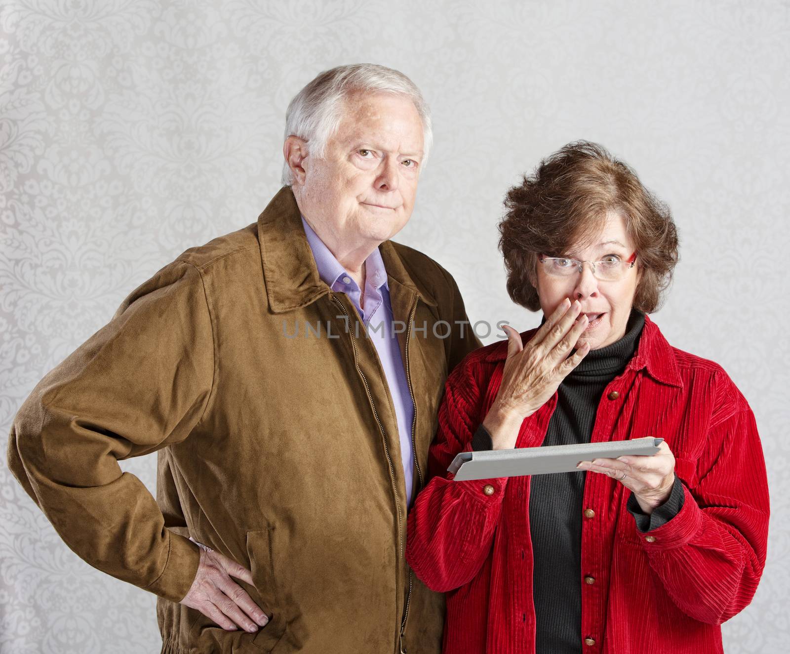Suspicious man and embarrassed woman holding tablet