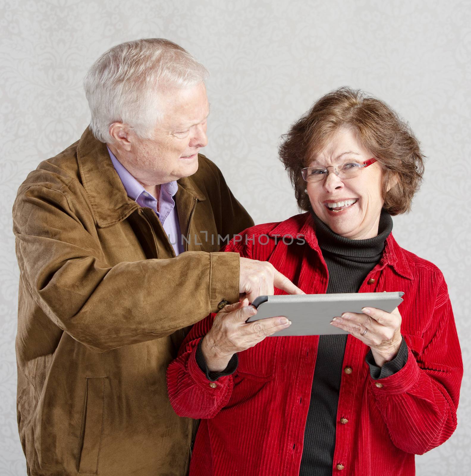 Confused man pointing at smiling womans tablet