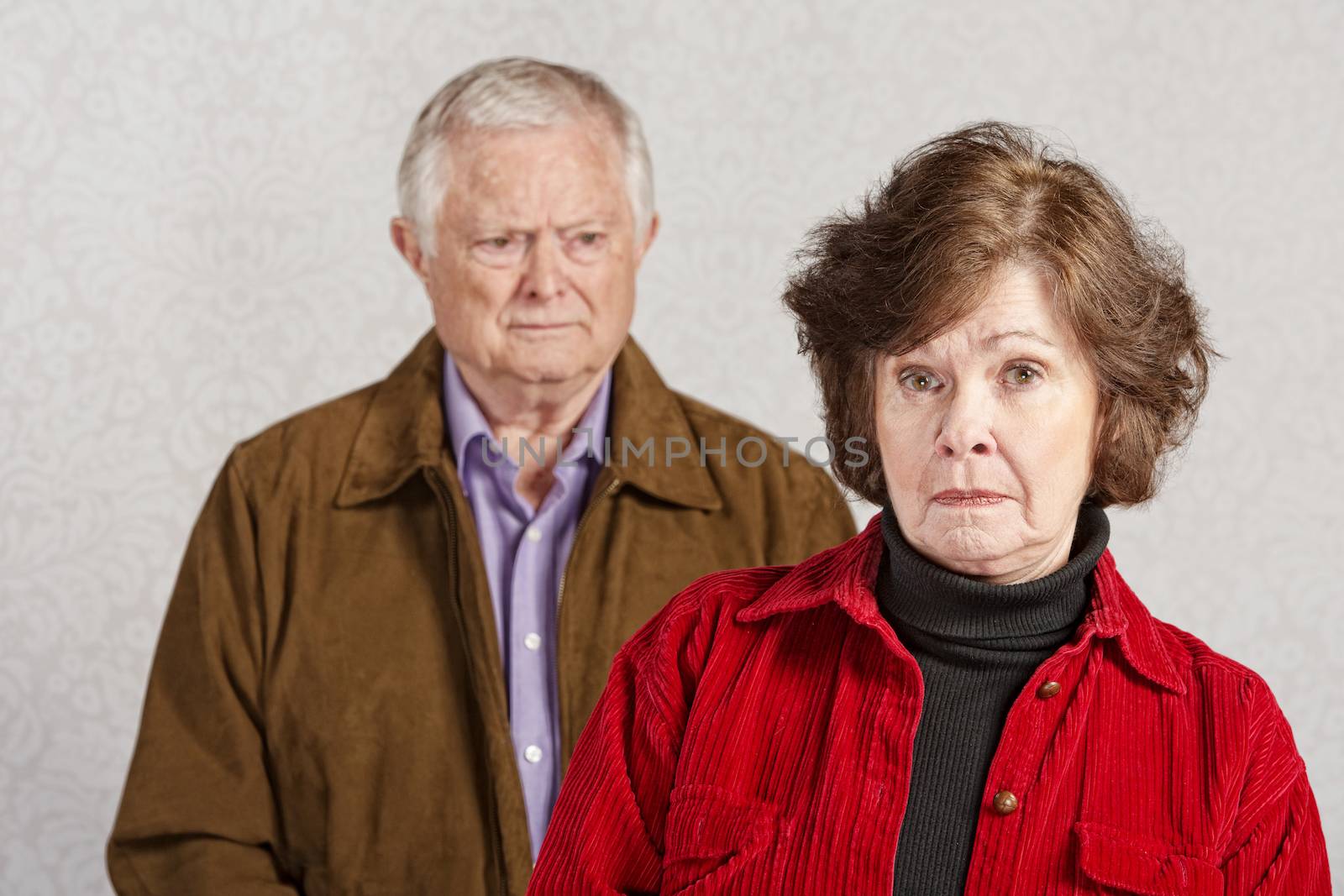 Unhappy European male and female senior couple
