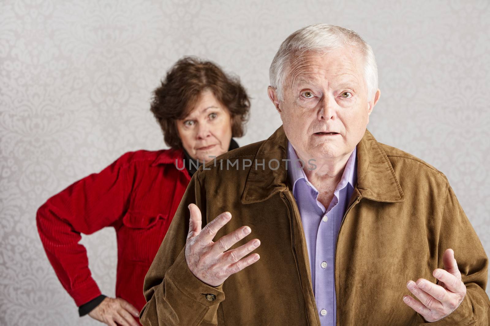 Frustrated older man with hands up and annoyed woman