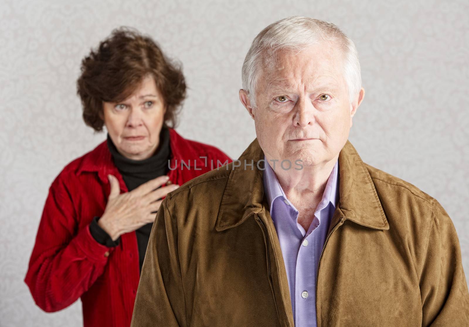Concerned senior woman with hand on chest behind sad man