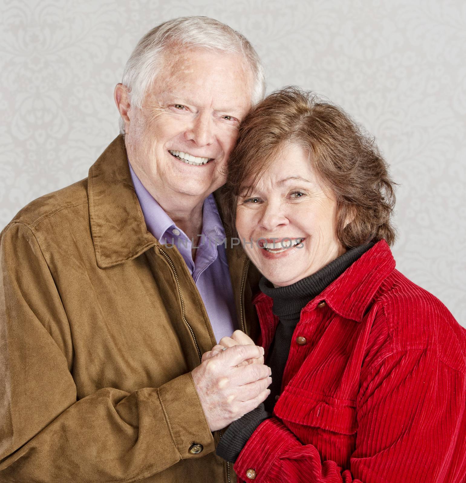 Smiling Caucasian older couple embracing and holding hands
