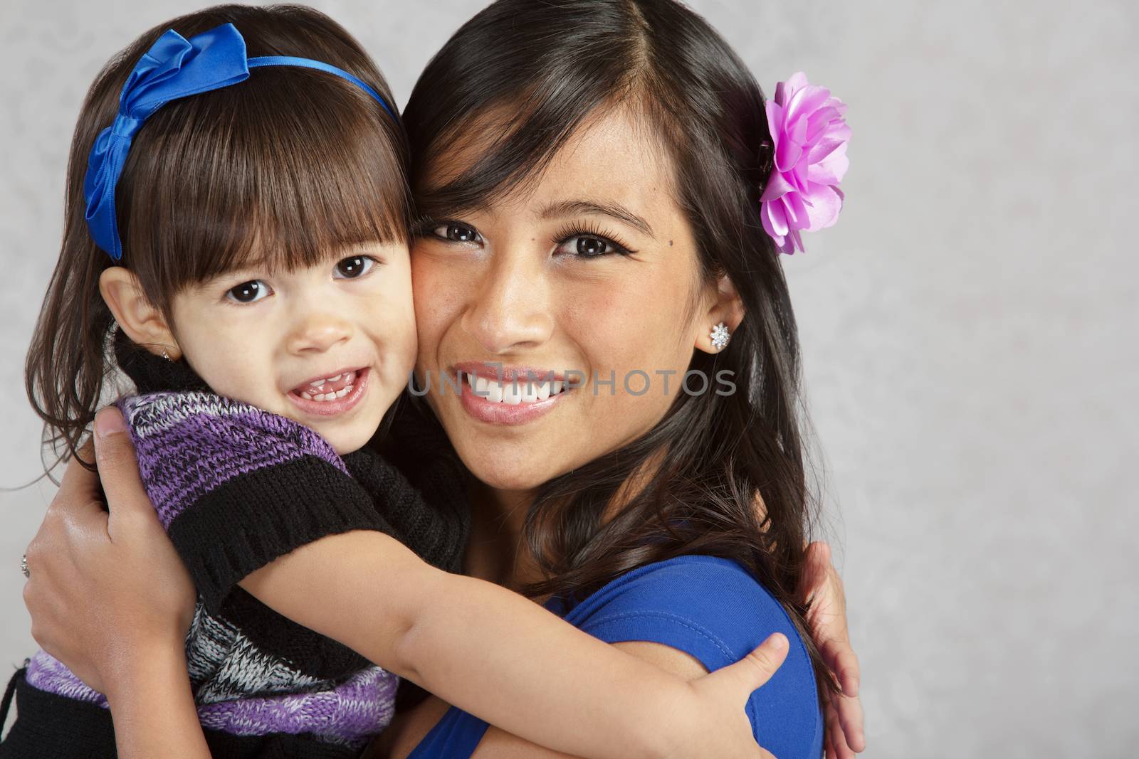 Happy young mother and female toddler hugging each other