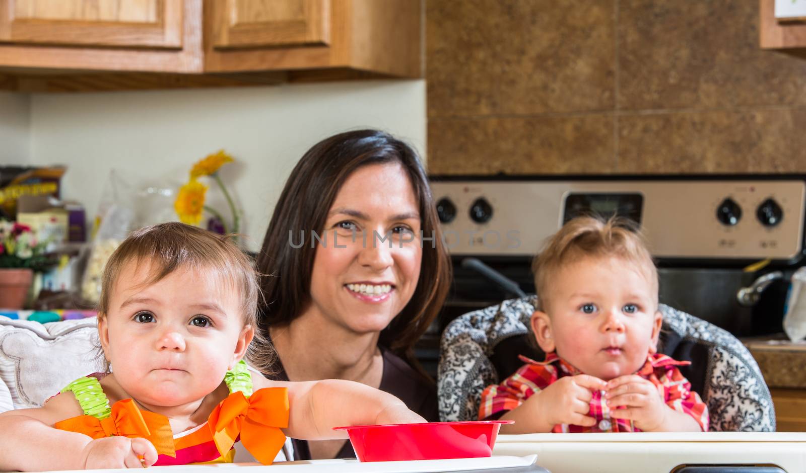 A mother in the kitchen poses with babies