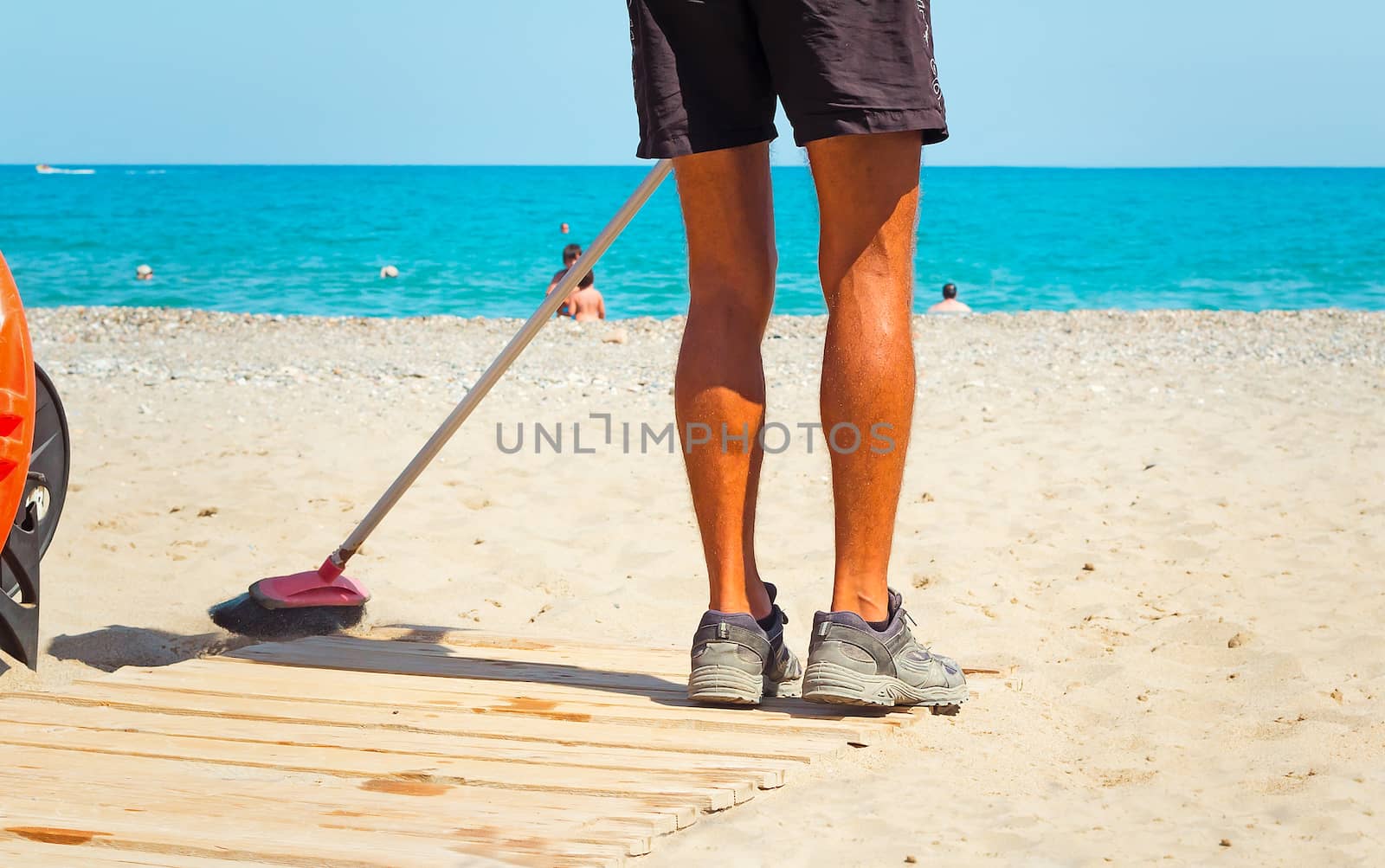 The worker on a beach cleans garbage on sand of a sea beach after a storm.