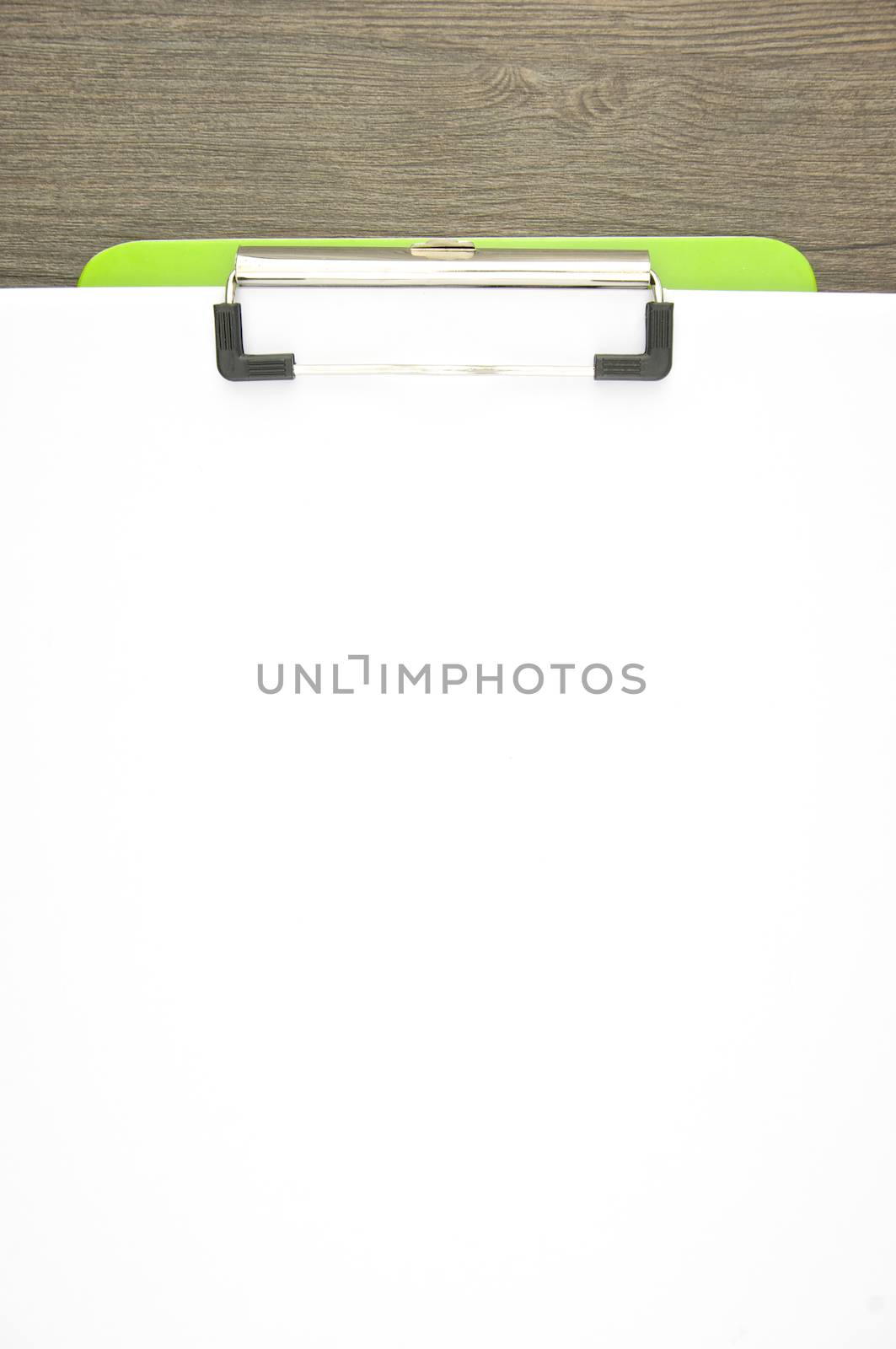 Write blank paper clip on green clipboard with wood background.