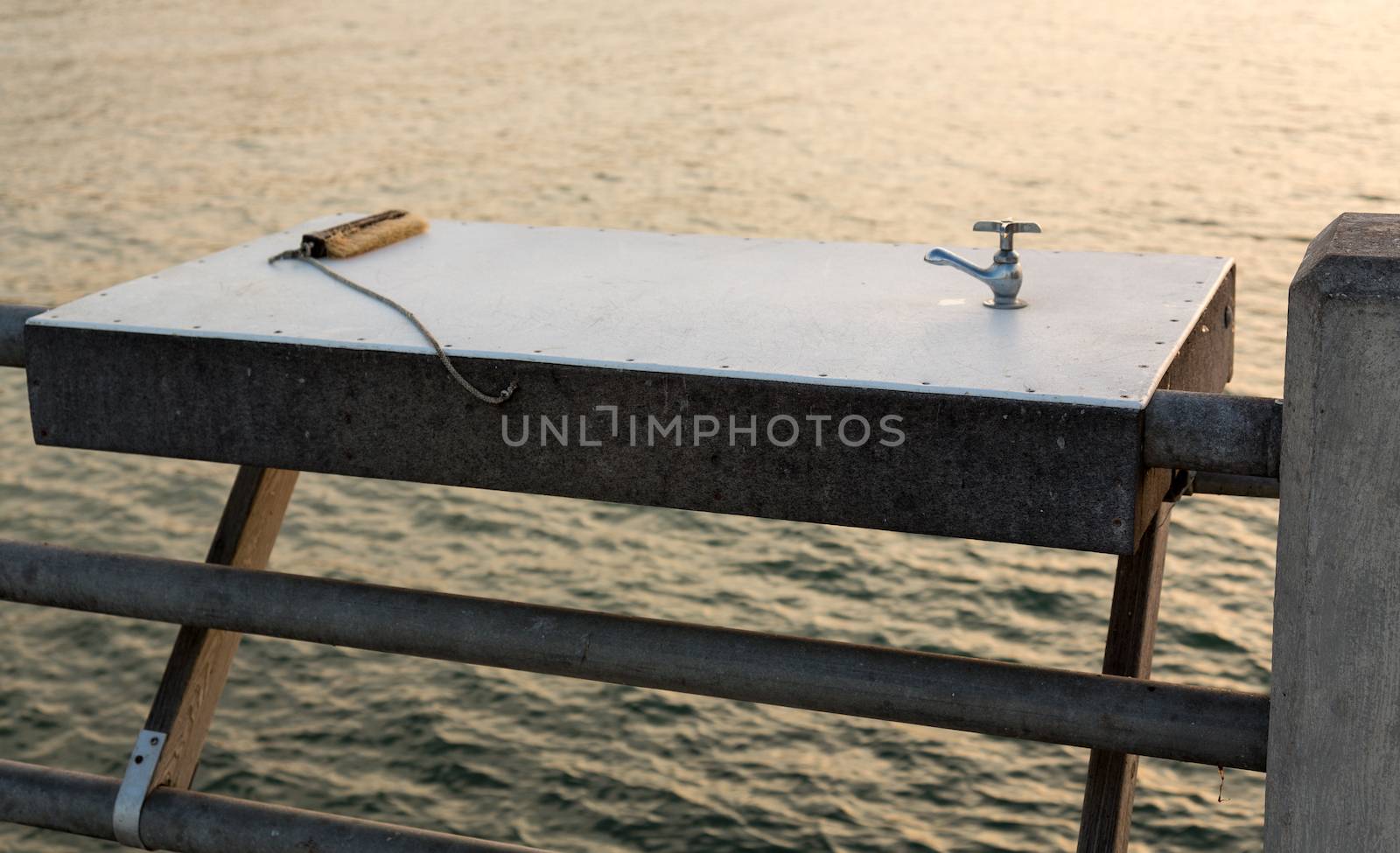 Metal table with tap or faucet for washing and cleaning fish with brush on pier off coast of Florida