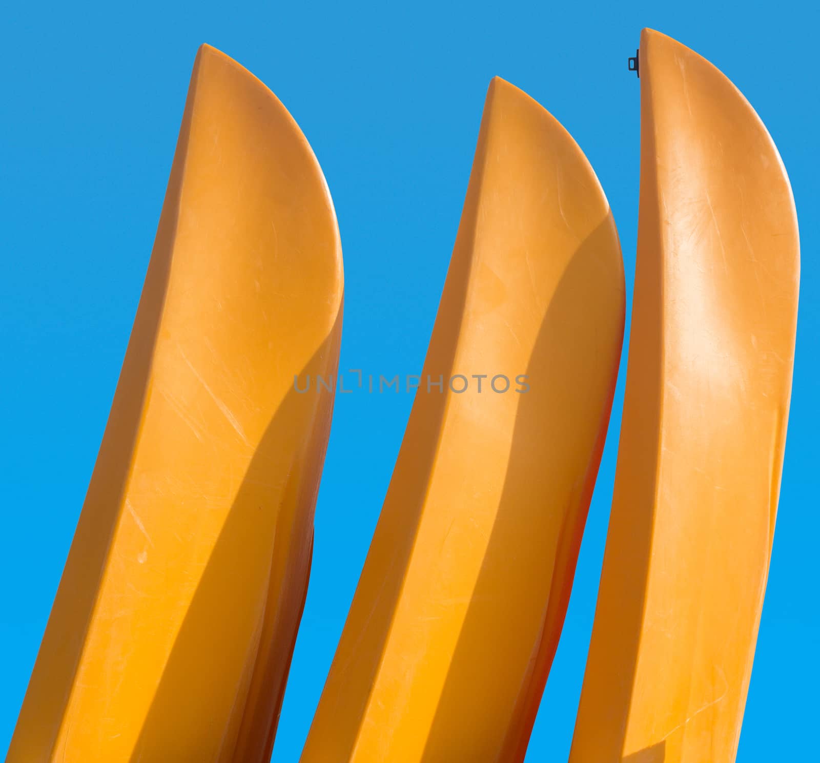 Three yellow prows of canoes or kayak with clipping path to allow easy isolation from blue sky behind the boats