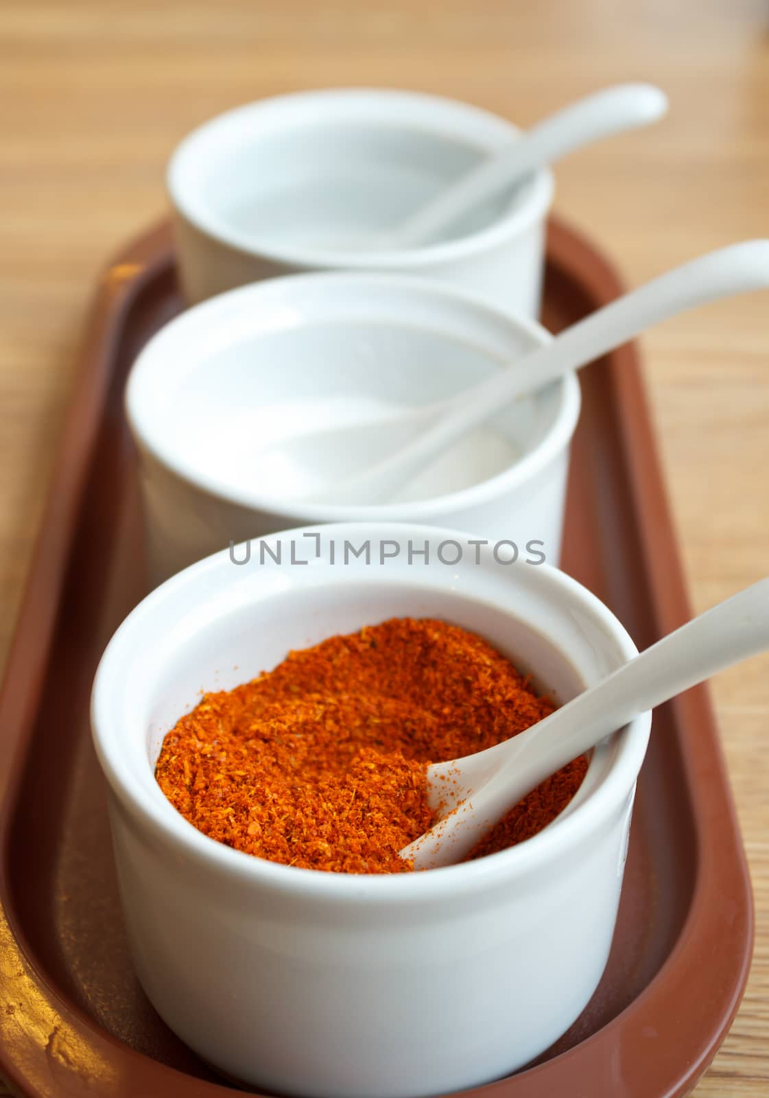 Cayenne pepper in white cups and spoons