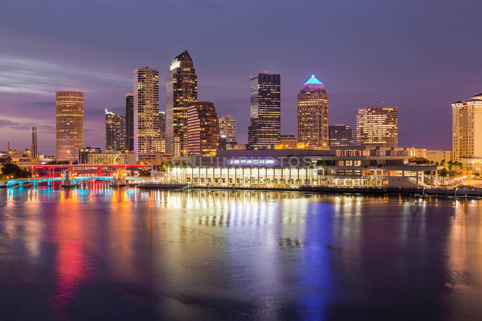 Florida skyline at Tampa with the Convention Center on the riverbank. Sun is just setting at dusk giving a fiery glow to the night sky.
