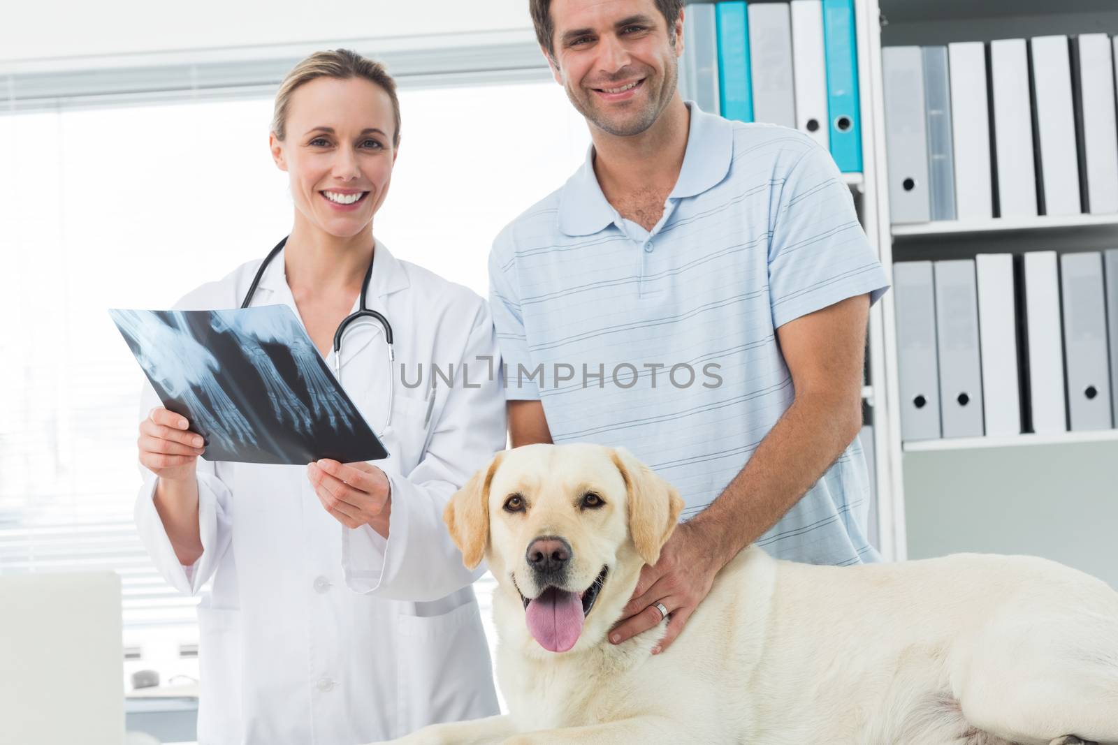 Portrait of happy pet owner and veterinarian with Xray of dog in hospital