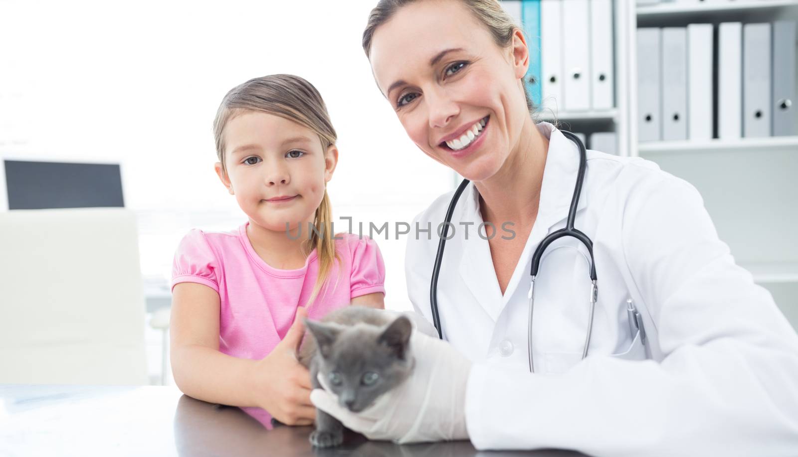 Portrait of female vet and girl with kitten in clinic