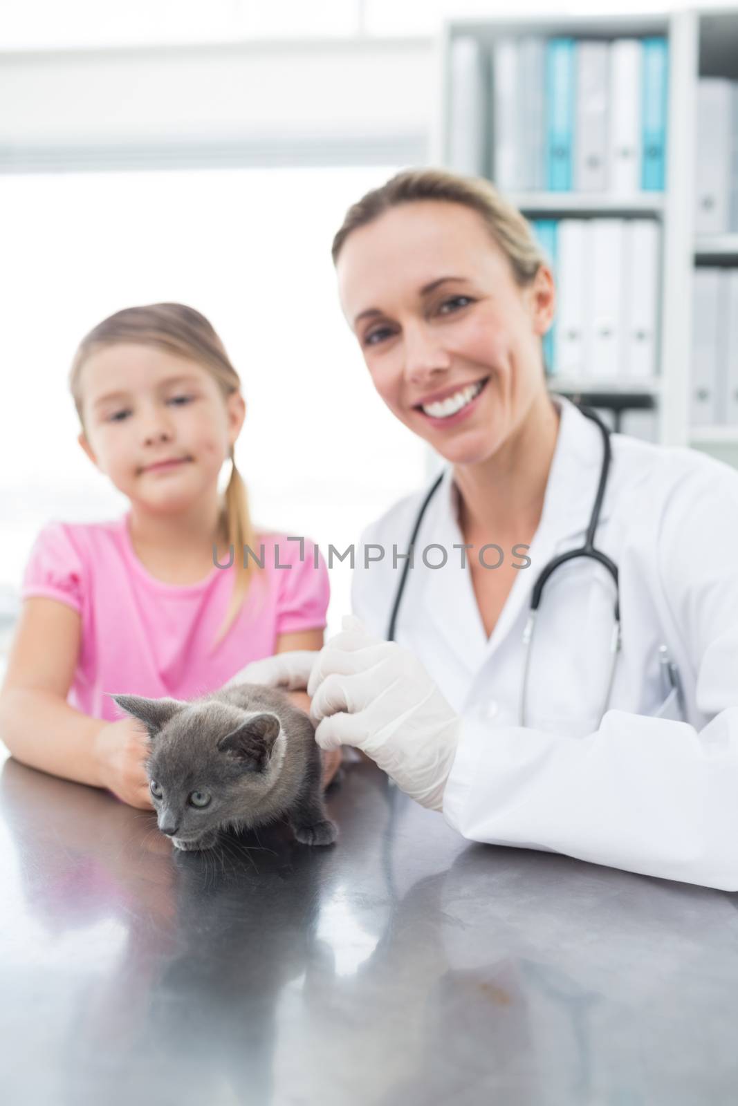 Portrait of female veterinary and girl with kitten in clinic