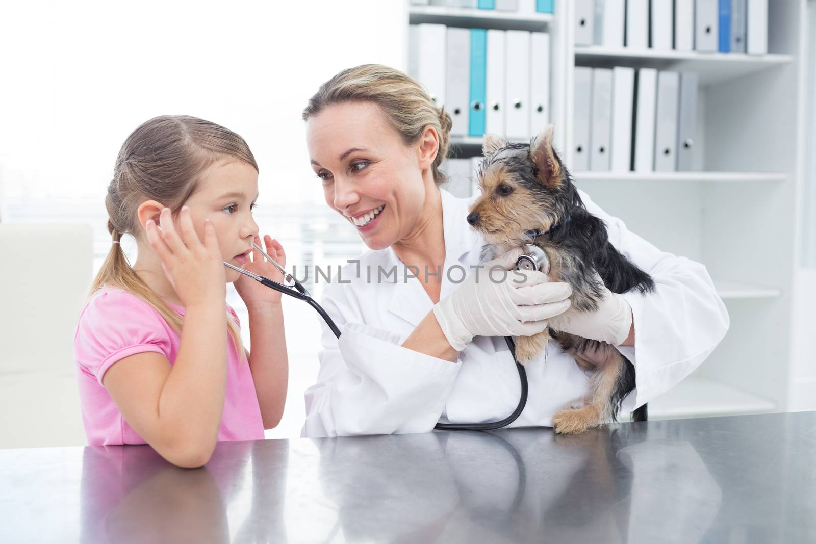 Vet with girl examining puppy by Wavebreakmedia