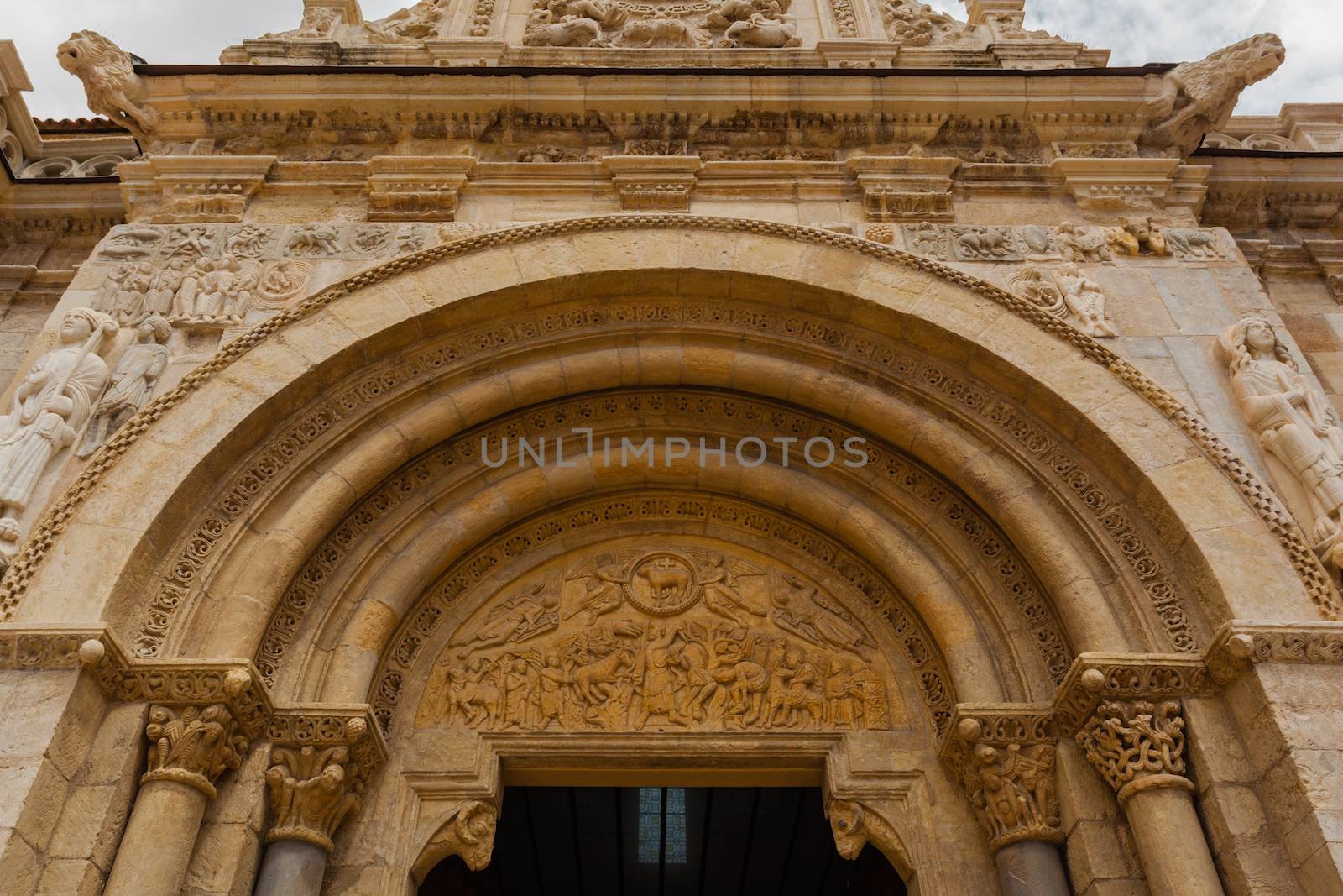wide view of romanesque arhivolts and carved tympanum in the main entrance door of the San Isidoro Collegiate church in Leon, Spain