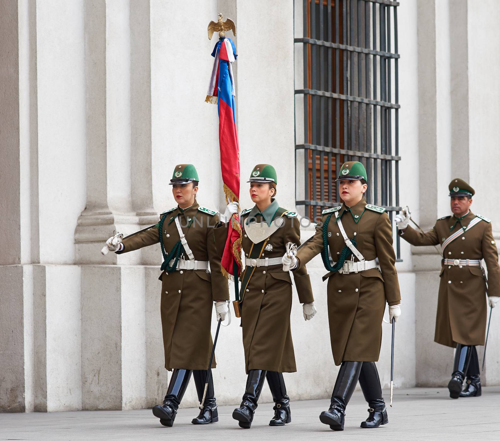 Female members of the Carabineros marching with a ceremonial flag as part of the changing of the guard ceremony at La Moneda in Santiago, Chile