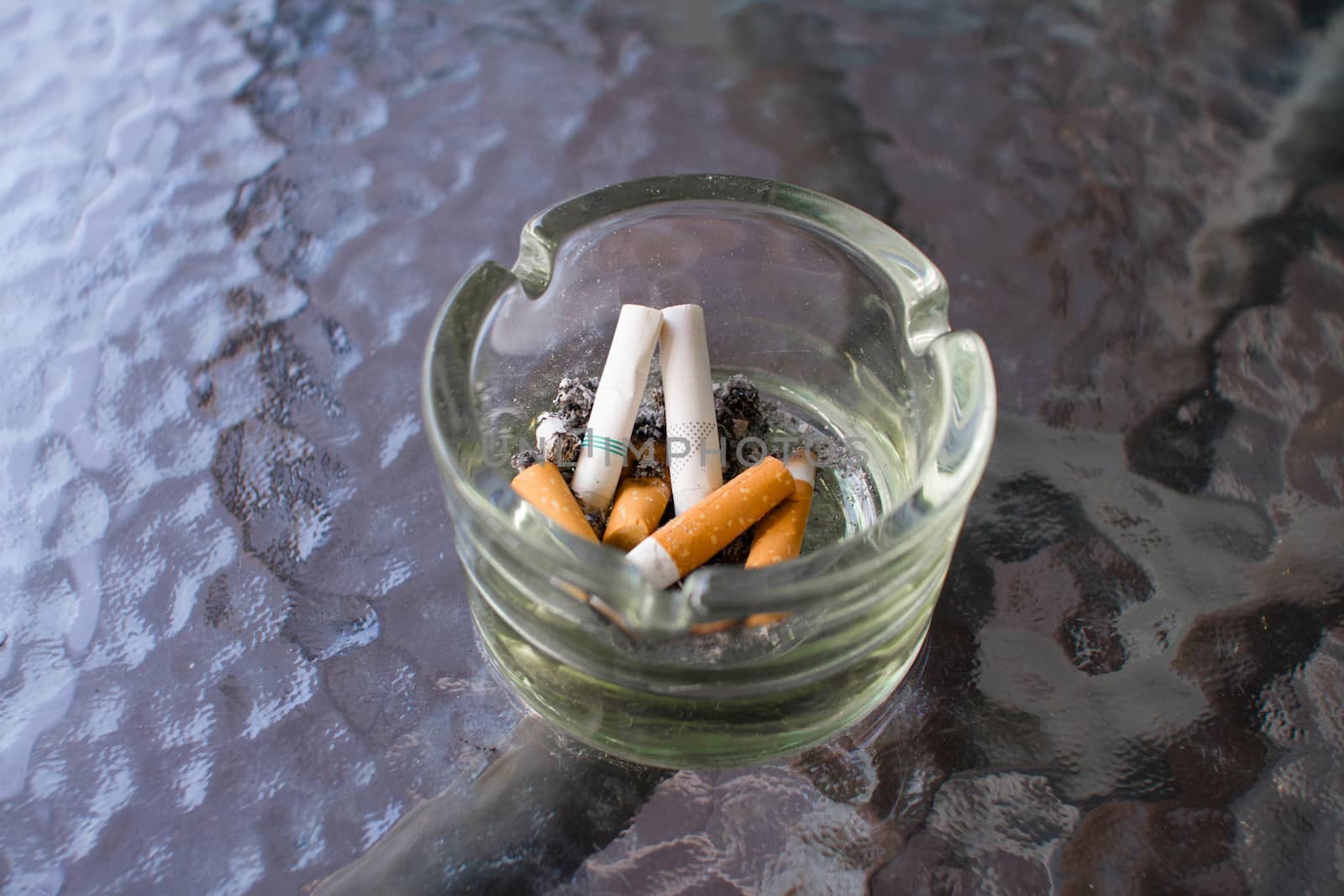 Overhead of burning cigarette in ashtray.