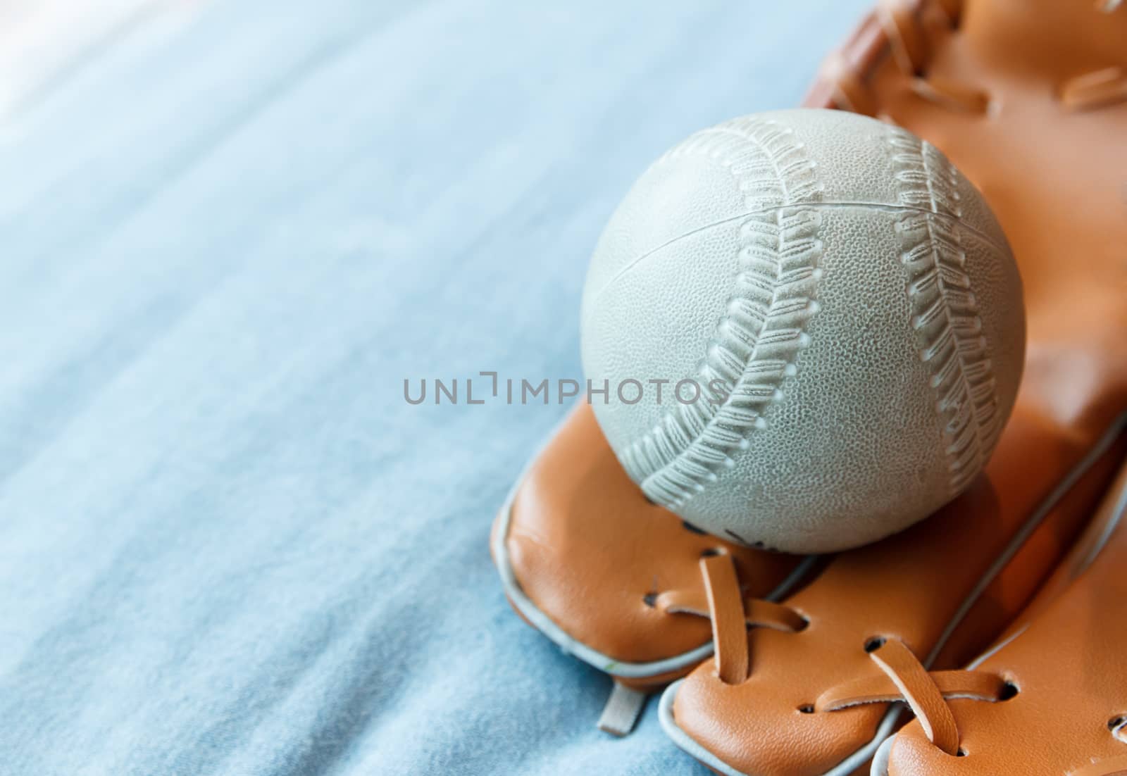 Old baseball in a glove on blue bed