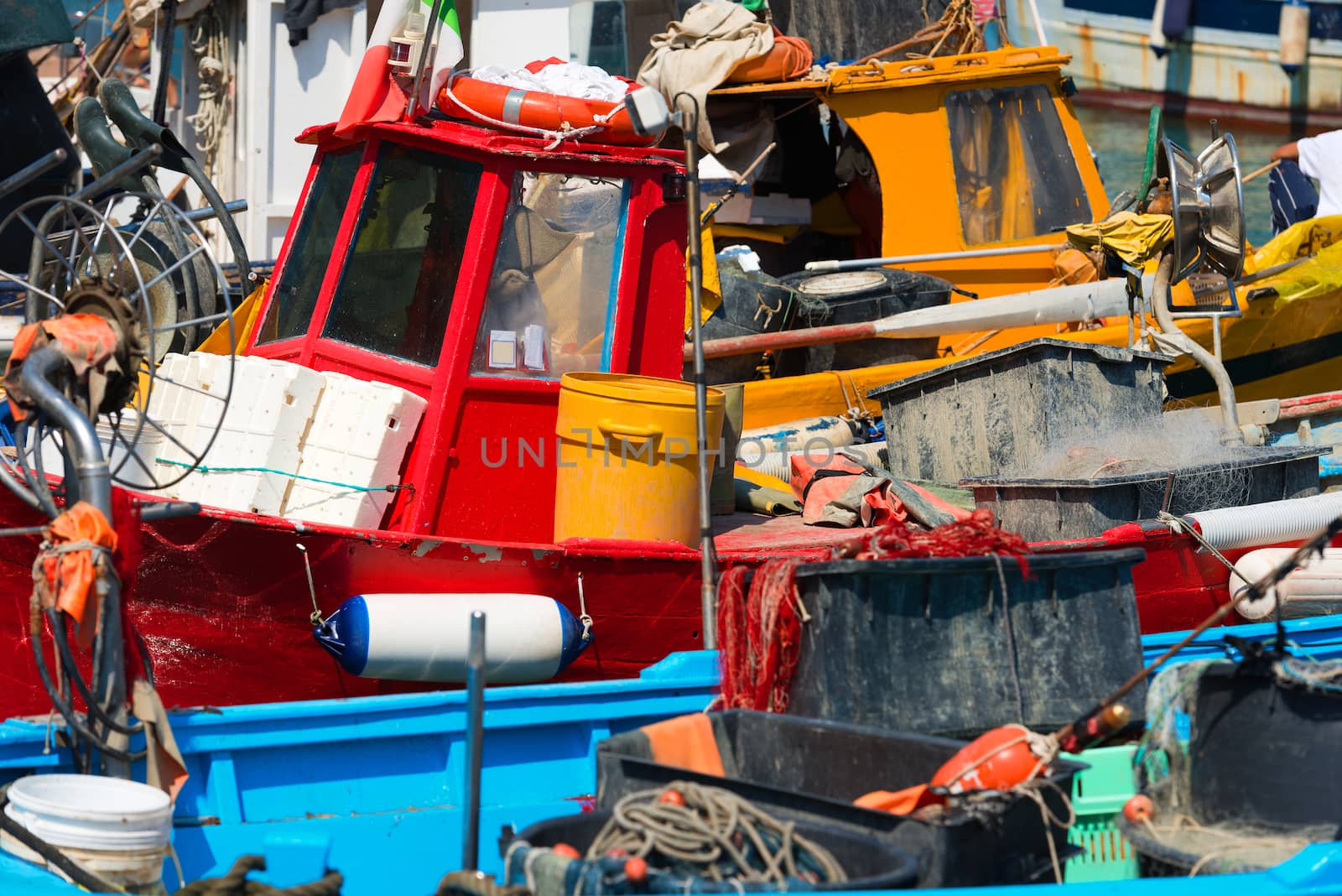 Small fishing boats, red, yellow, blue and white with fishing equipment docked in port - Lerici, La Spezia, Liguria, Italy