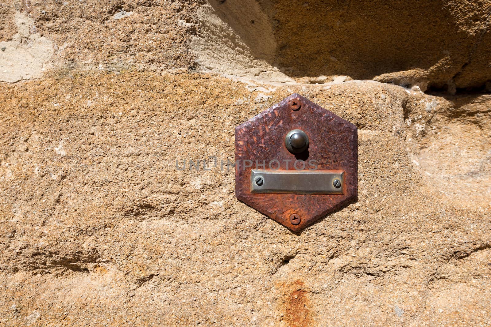 Rusty doorbell button on brown stone wall in San Gimignano town (UNESCO heritage), Siena, Tuscany, Italy
