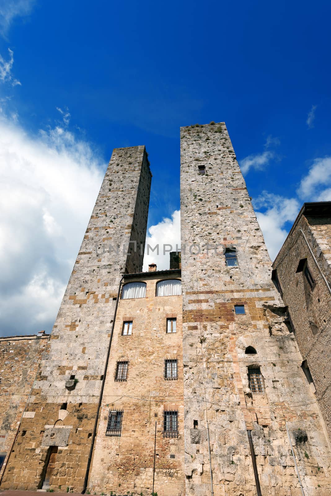 Two towers and houses in Piazza delle Erbe, San Gimignano medieval town (UNESCO heritage), Siena, Tuscany, Italy