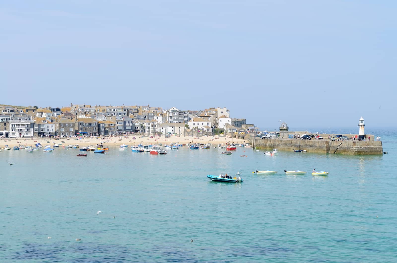 Seaside harbour showing fishing boats and lighthouse in St Ives, Cornwall, England