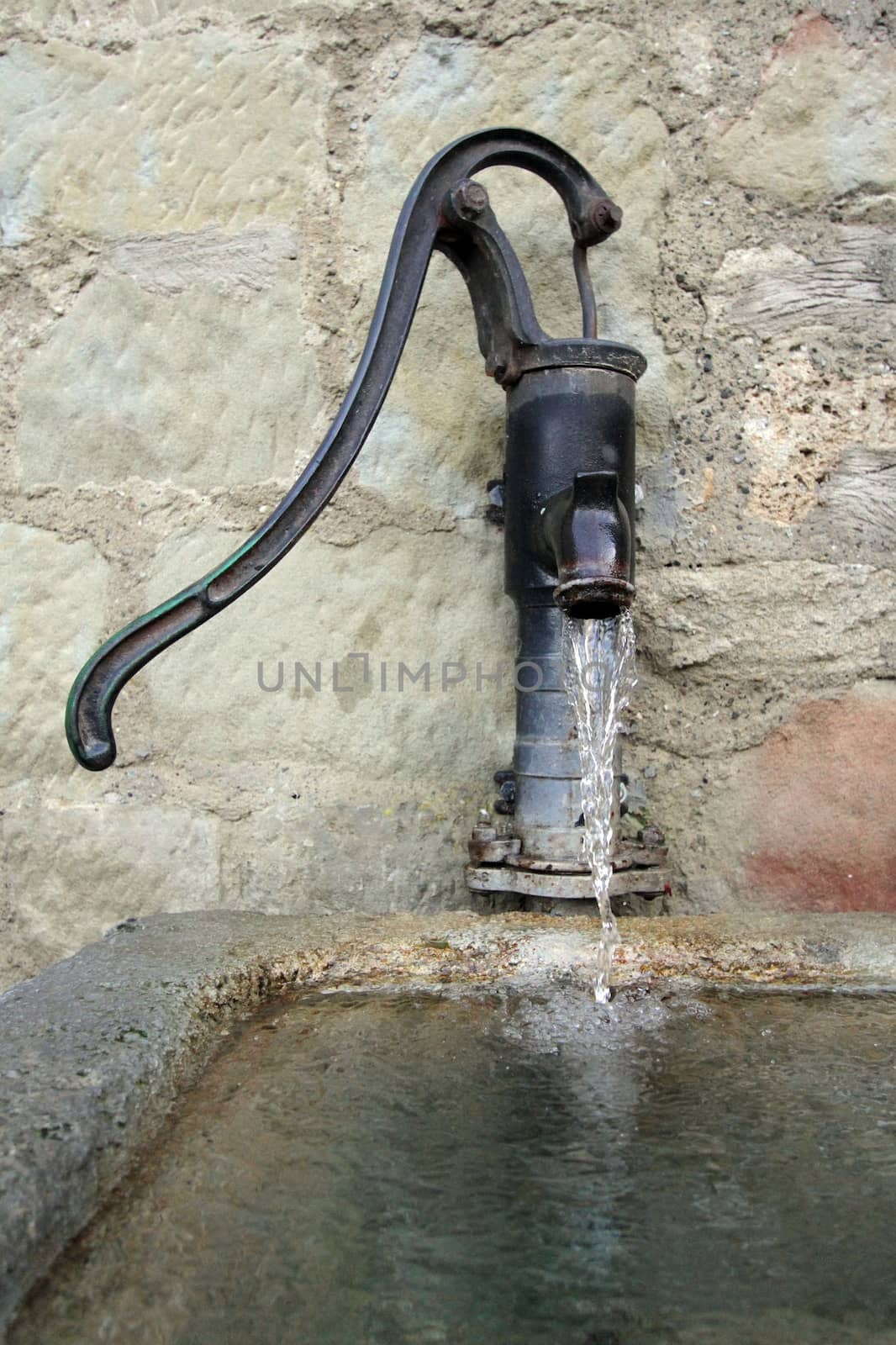 Vintage iron fountain against old stone wall