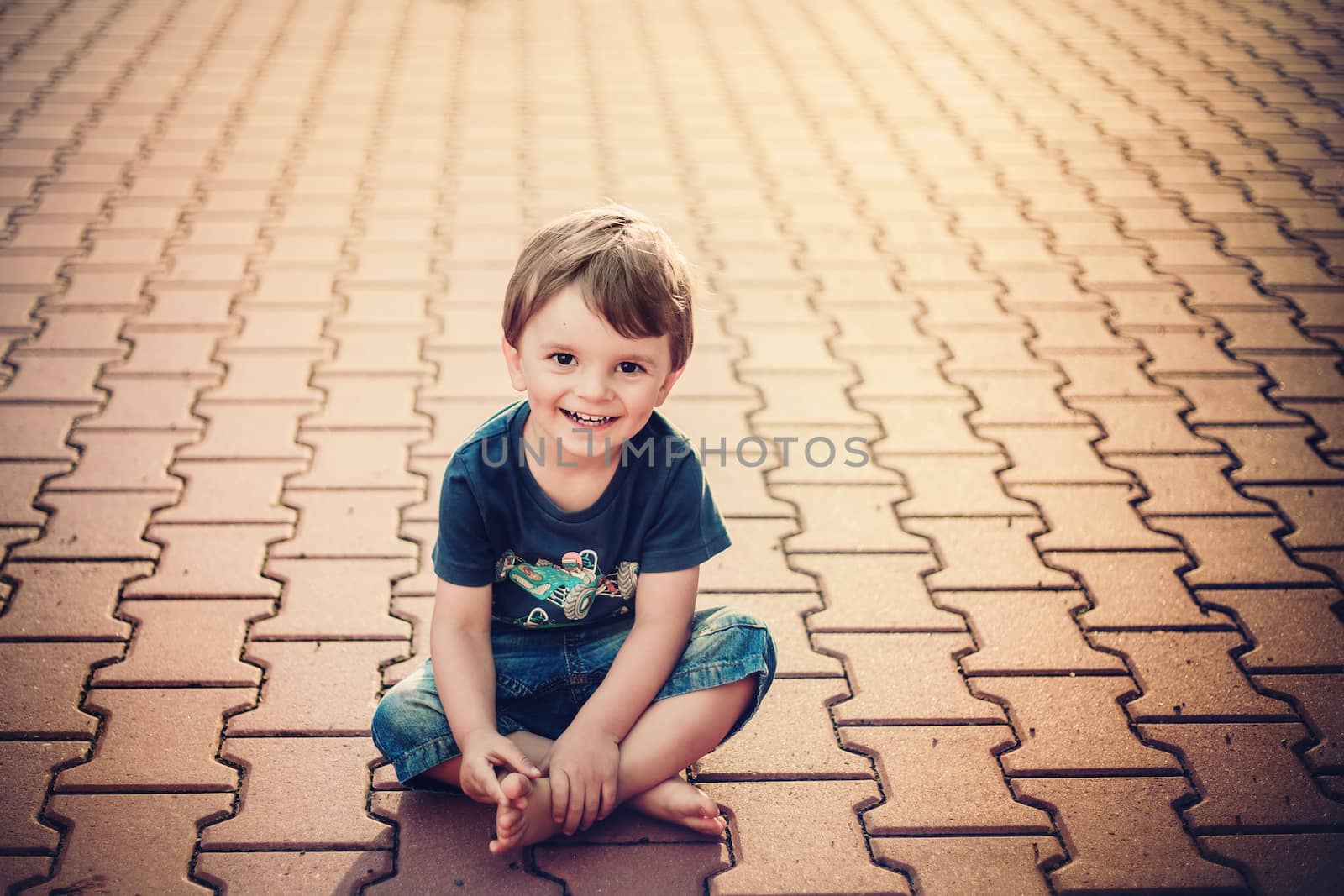 smiling little boy sitting on the ground and looking into the camera